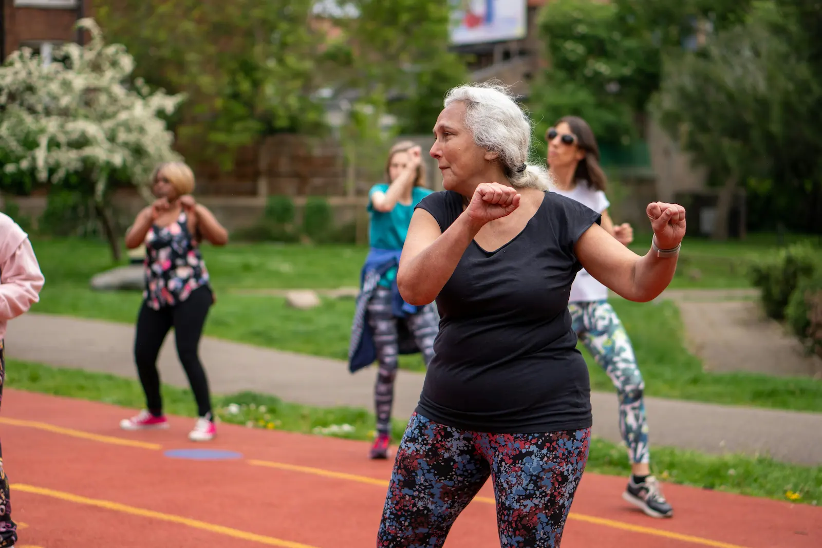 diverse older women staying active by doing yoga and dance on the track in the park